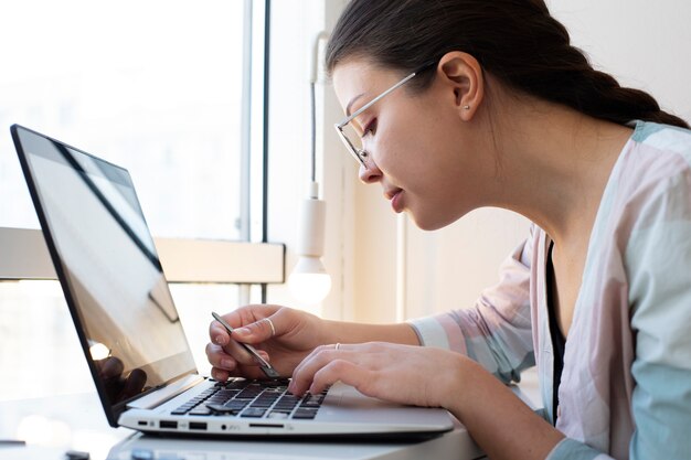 Mujer joven limpiando el teclado de su computadora portátil