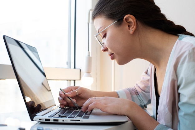 Mujer joven limpiando el teclado de su computadora portátil