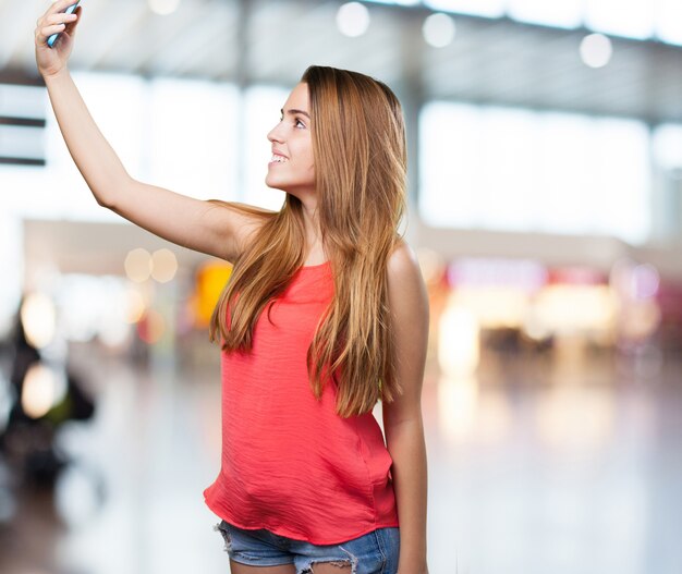 mujer joven linda que toma una autofoto en el fondo blanco