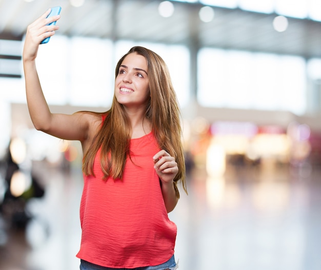 mujer joven linda que toma una autofoto en el fondo blanco