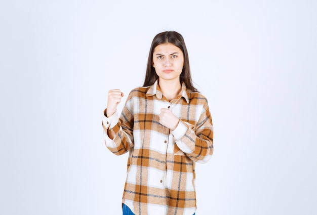 Foto gratuita mujer joven lista para la pelea en la pared blanca.