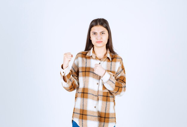 mujer joven lista para la pelea en la pared blanca.