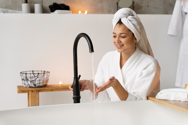 Mujer joven llenando la bañera y preparándose para tomar un baño