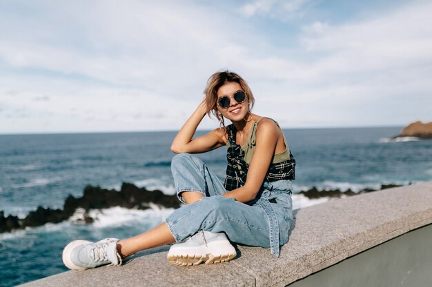 Mujer joven, llevando, camisa vaquera, con, gafas de sol, posar, en, playa