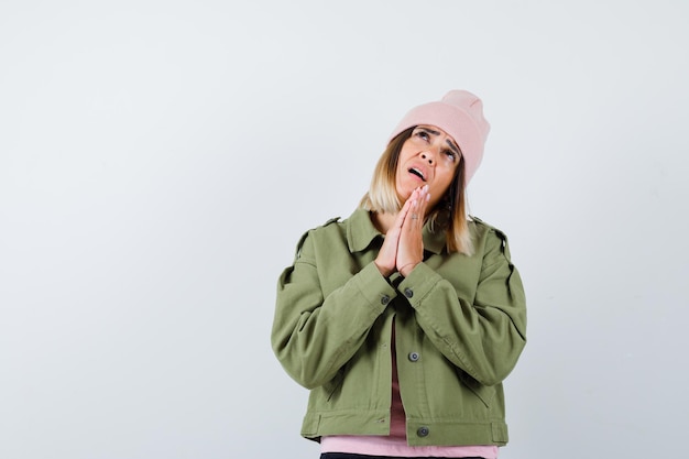 Mujer joven, llevando, un, chaqueta, y, un, sombrero rosa, rezando