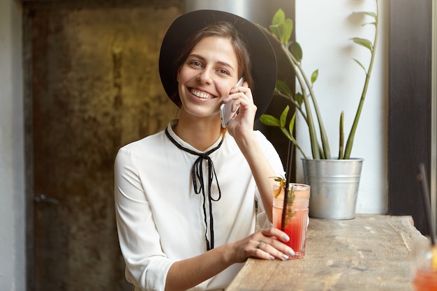 Foto gratuita mujer joven, llevando, sombrero grande, en, café