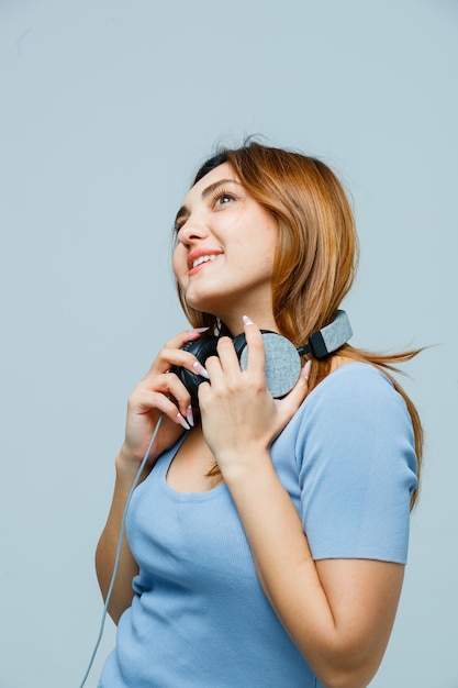 Mujer joven, manos de valor en cartera, en, auriculares, mientras, mirar hacia arriba