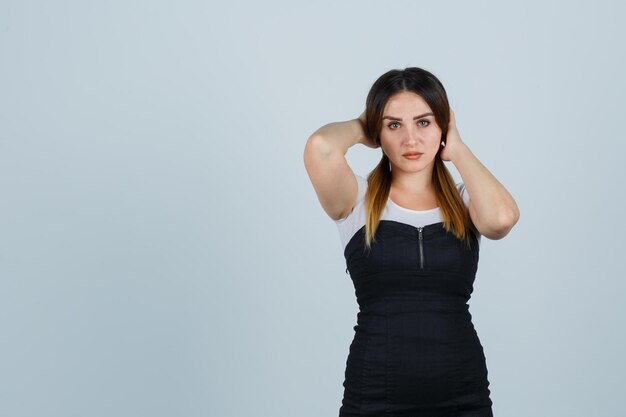 Mujer joven, manos de valor en cartera, detrás de la cabeza