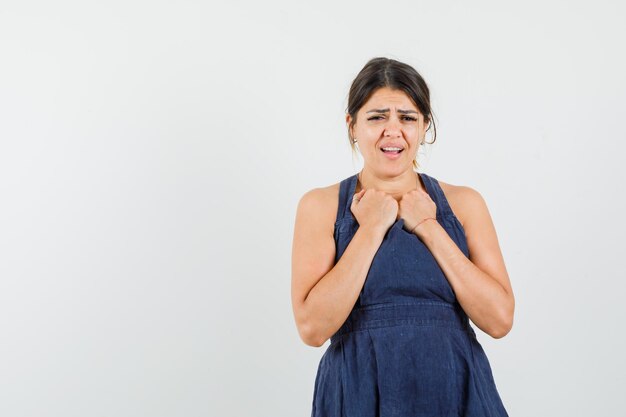 Mujer joven manteniendo los puños cerrados en el pecho en la vestimenta