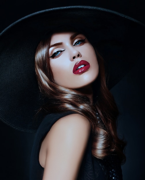 Mujer joven con maquillaje brillante y sombrero negro