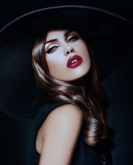 Mujer joven con maquillaje brillante y sombrero negro