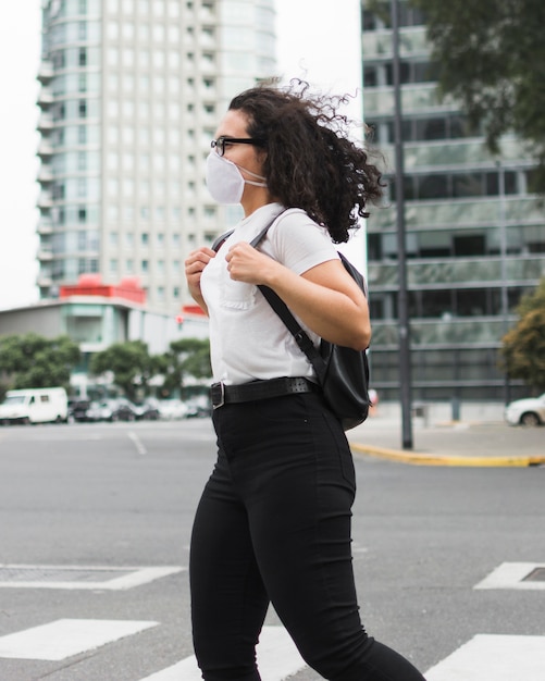 Mujer joven con máscara médica estar afuera