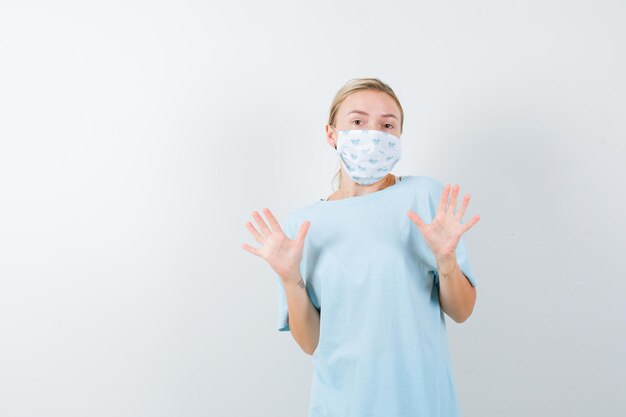 Mujer joven con una máscara médica mostrando gesto de parada