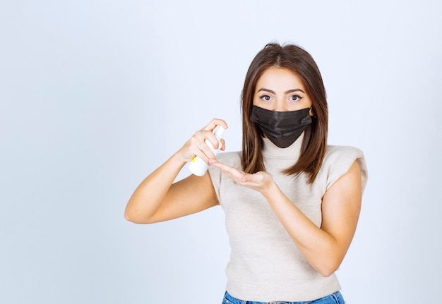 Foto gratuita mujer joven en una máscara médica negra con un spray