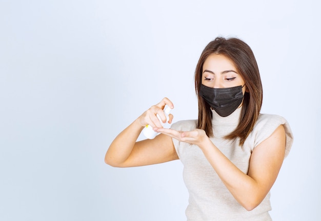 Foto gratuita mujer joven en una máscara médica negra con un spray