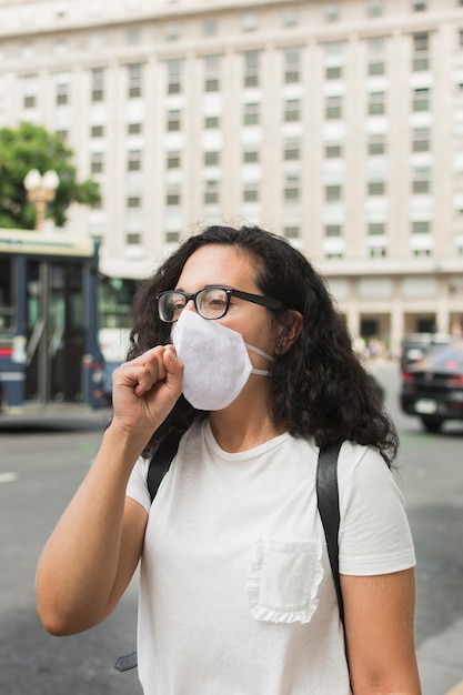 Foto gratuita mujer joven con una máscara médica y tos al aire libre