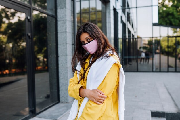 Mujer joven con máscara posando en la calle.