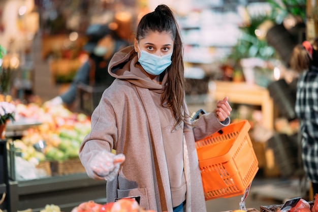 Mujer joven con máscara protectora hace compras en el supermercado