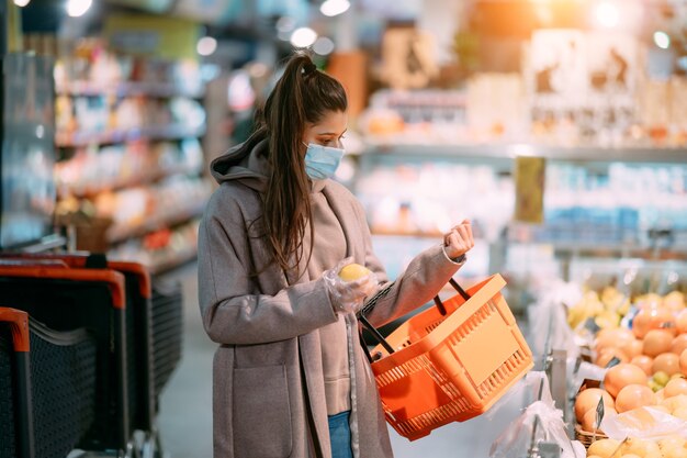 Mujer joven con máscara protectora hace compras en el supermercado