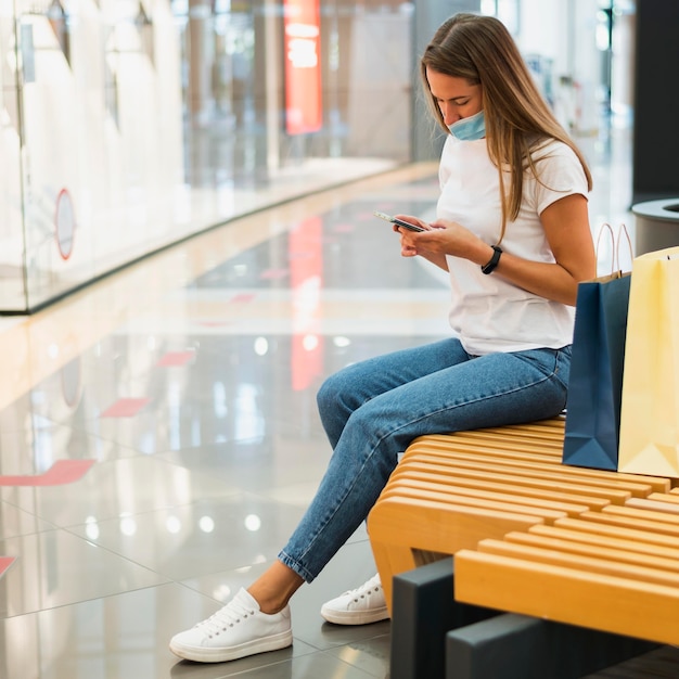 Mujer joven con mascarilla comprobación de teléfono móvil