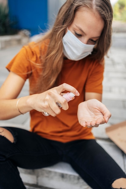 Mujer joven con mascarilla desinfectando sus manos