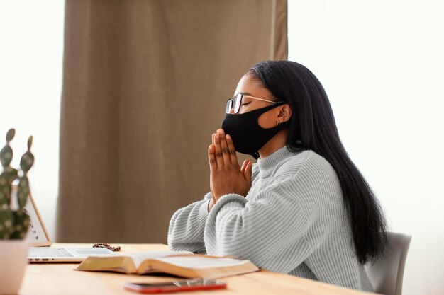 Mujer joven con una mascarilla mientras rezaba