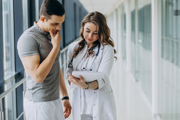 Mujer joven médico practicante consulta paciente masculino