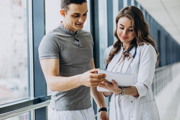 Mujer joven médico practicante consulta paciente masculino