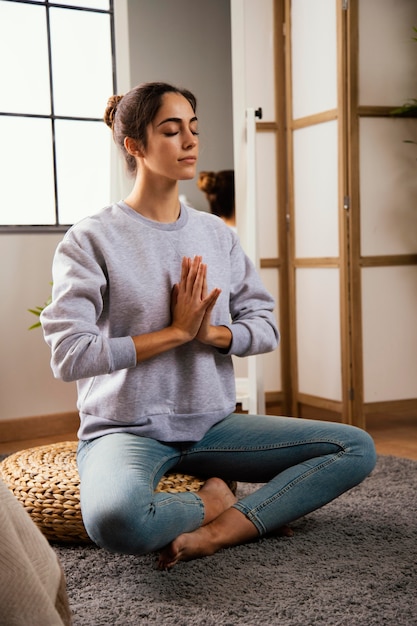 Mujer joven meditando en casa