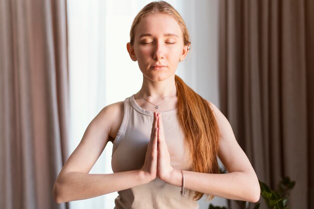 Mujer joven meditando en casa