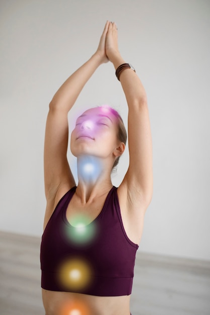 Mujer joven meditando con chakras en su cuerpo