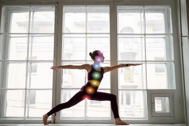 Mujer joven meditando con chakras en su cuerpo