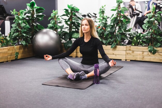 Mujer joven meditando en la estera del ejercicio