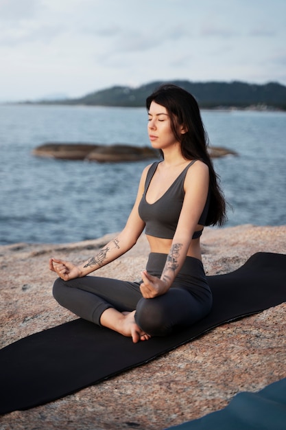 Mujer joven meditando en mat full shot