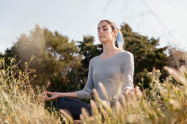 Foto gratuita mujer joven meditando en la naturaleza