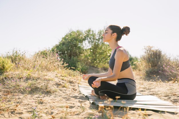 Mujer joven meditando por la playa