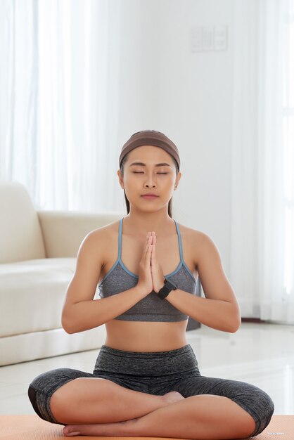 Mujer joven meditando sobre estera en paz