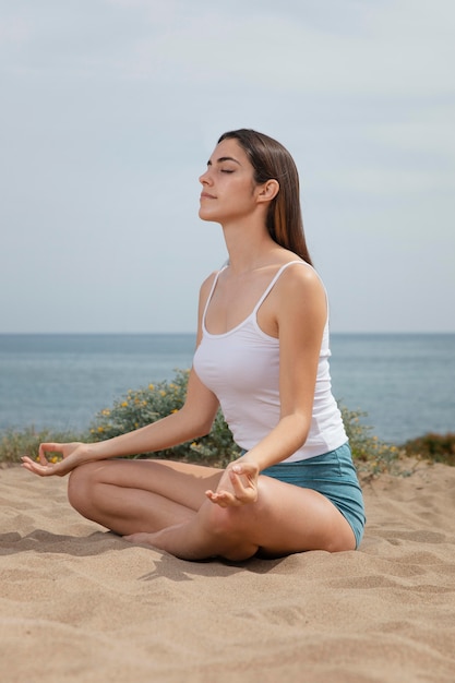 Foto gratuita mujer joven, meditar, en, arena