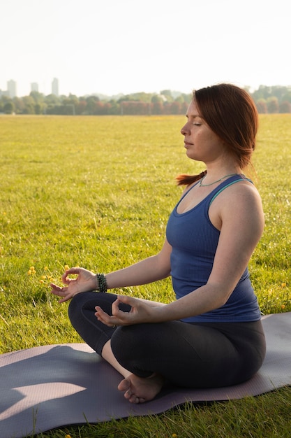 Mujer joven, meditar, en, estera de yoga, aire libre