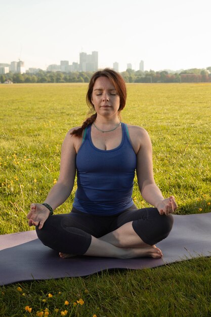 Mujer joven, meditar, en, estera de yoga, aire libre