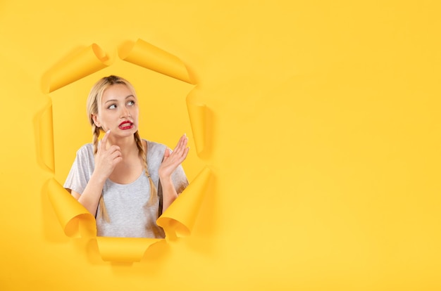 Mujer joven con mirada curiosa a un lado sobre fondo de papel amarillo comercial publicidad facial