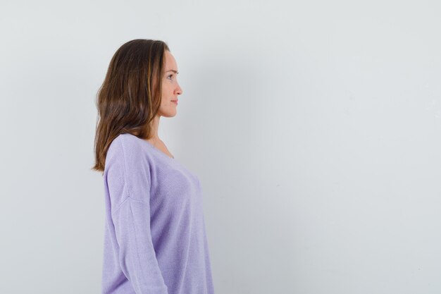 Mujer joven mirando hacia adelante en blusa lila y mirando complacido. . espacio para texto