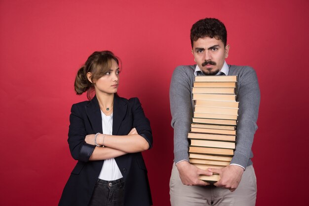 Mujer joven mirando al hombre que lleva un montón de libros