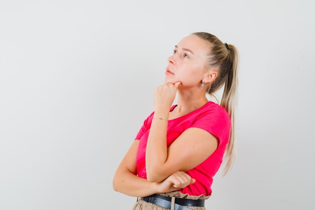 Mujer joven mirando hacia arriba en camisetas y pantalones y mirando pensativo