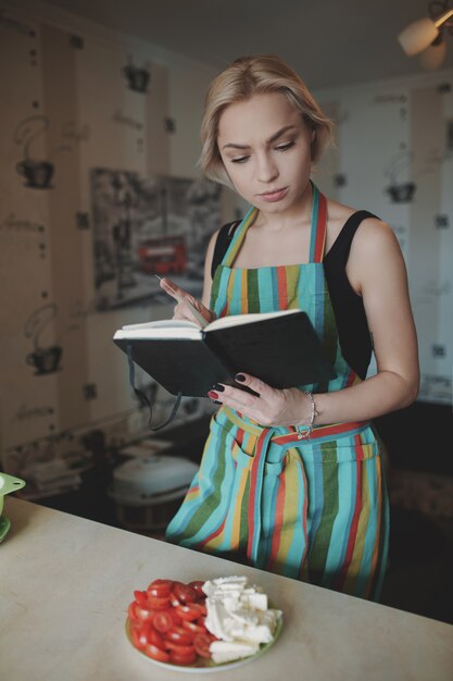 Mujer joven mirando hacia arriba en un libro de recetas