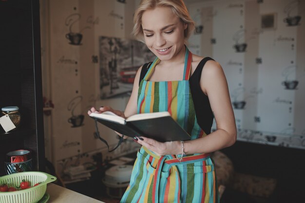 Mujer joven mirando hacia arriba en un libro de recetas