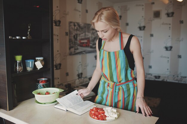 Mujer joven mirando hacia arriba en un libro de recetas