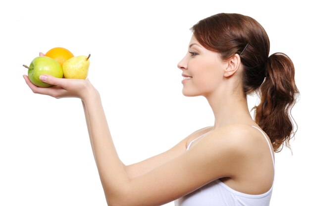 Mujer joven mirando ay los frutos en sus manos