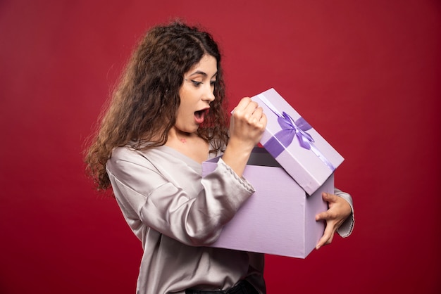 Mujer joven mirando caja de regalo y sorprenderse.