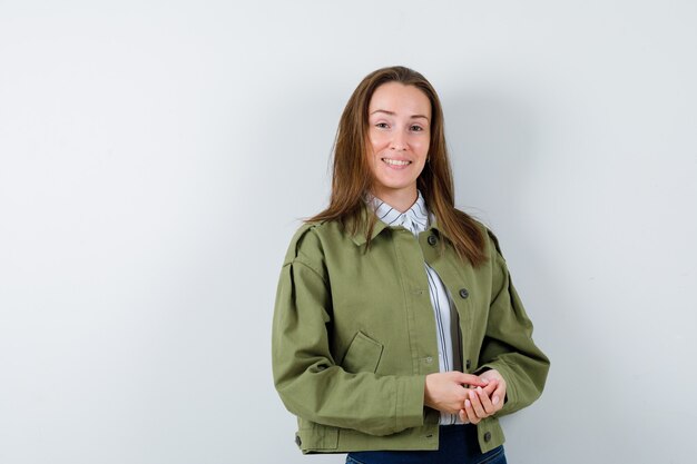 Mujer joven mirando a cámara en camisa, chaqueta y mirando alegre, vista frontal.